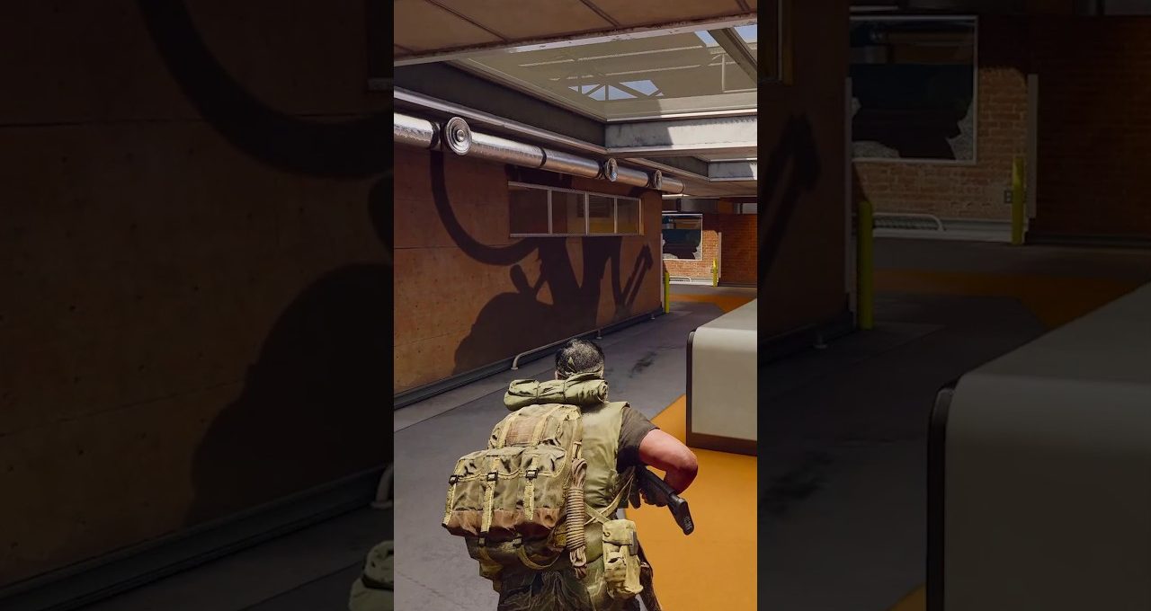 Soldier with large backpack and rifle crouching in industrial corridor under skylights