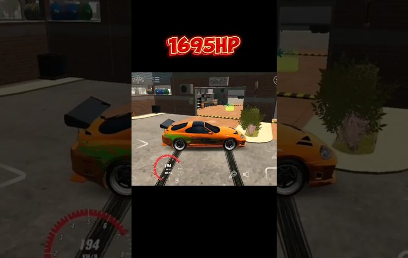 Orange sports car with green accents parked in a garage area, speed HUD visible