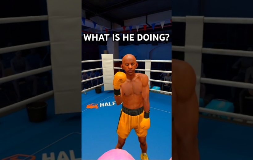 Boxer in yellow shorts and gloves standing in a boxing ring, raising fist.