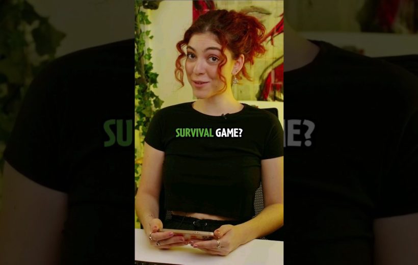 Young woman with red hair smiling while holding a smartphone, text "SURVIVAL GAME?" on shirt