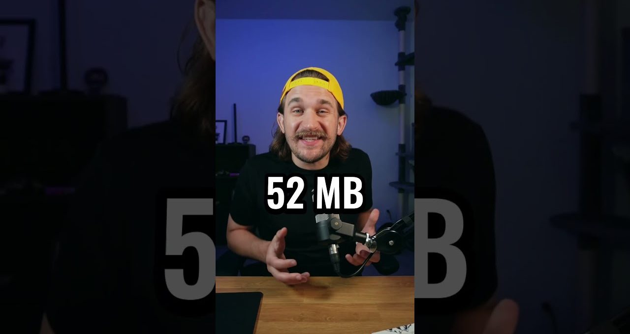 Man wearing yellow cap speaking into microphone at desk with "52 MB" text