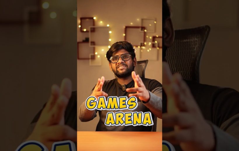 Man speaking enthusiastically at desk with "Games Arena" text and warm string lights