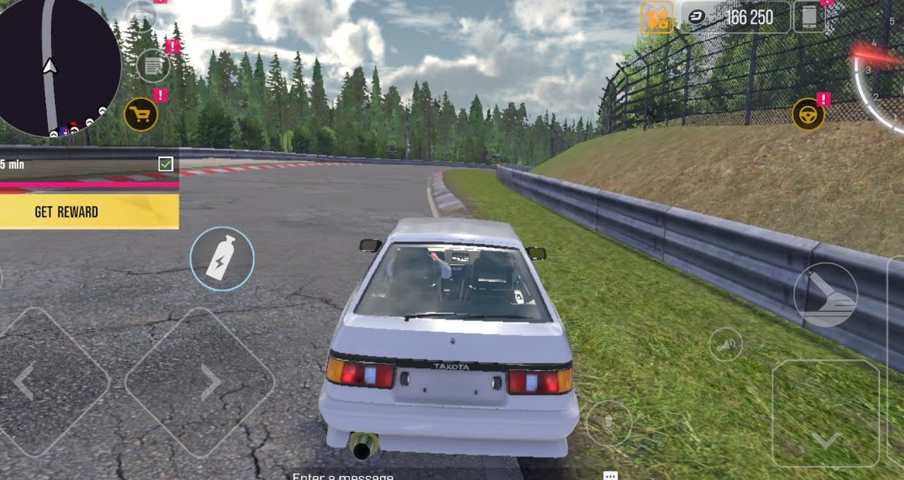 White hatchback racing car parked beside a racetrack barrier with forested backdrop