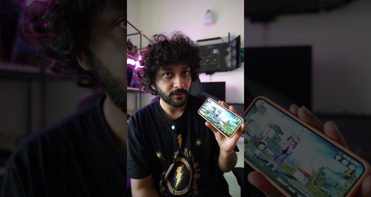 Young man with curly hair showing a smartphone displaying a video game screen