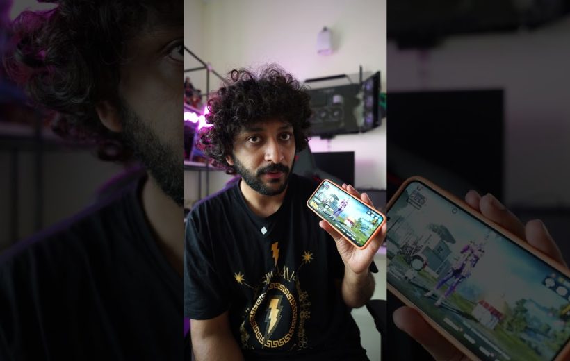 Young man with curly hair showing a smartphone displaying a video game screen