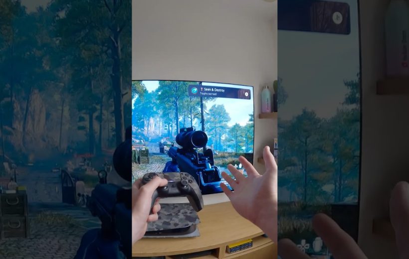 Person holding a game controller playing a first-person shooter on TV screen