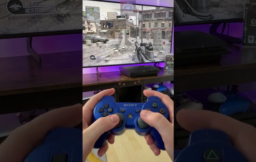 Hands holding a blue Sony controller playing a first-person shooter on TV