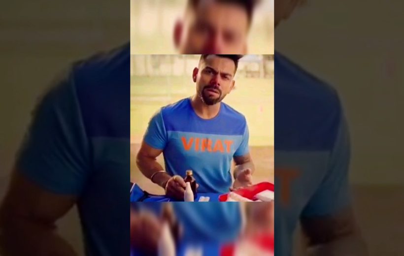 Man in blue t-shirt labeled "VIRAT" gesturing while holding a bottle at a table