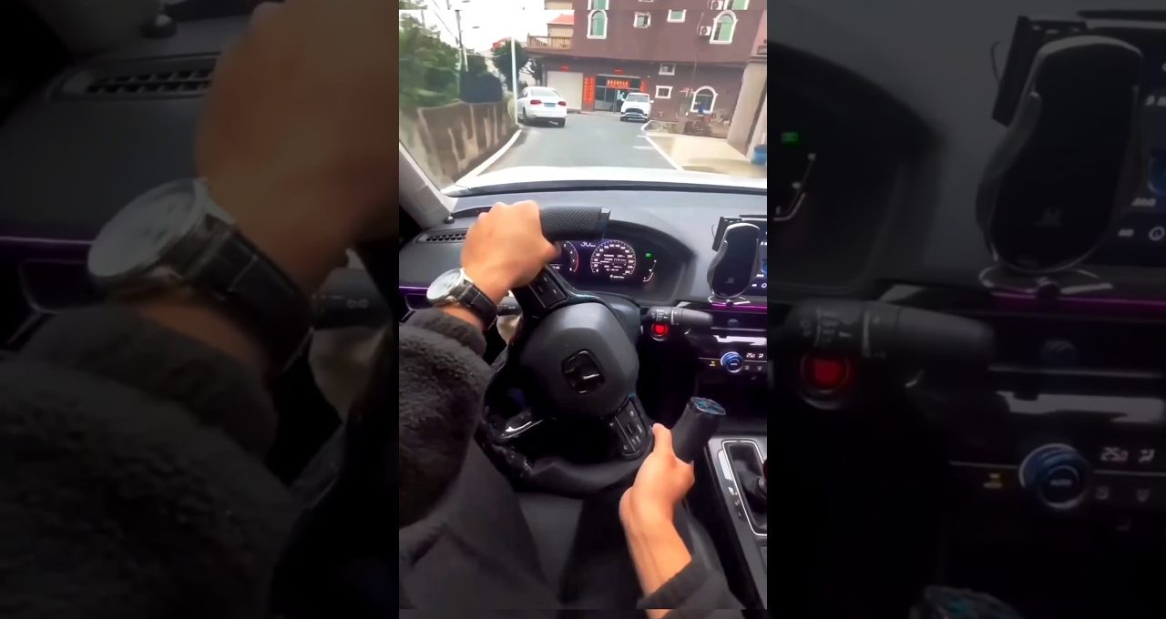 Driver's hands on steering wheel and gear knob while approaching a residential street