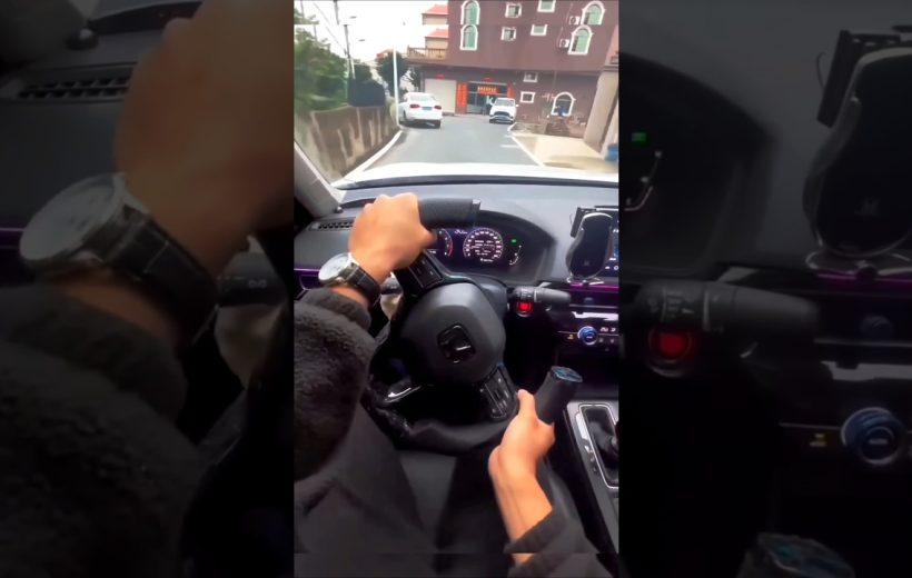 Driver's hands on steering wheel and gear knob while approaching a residential street