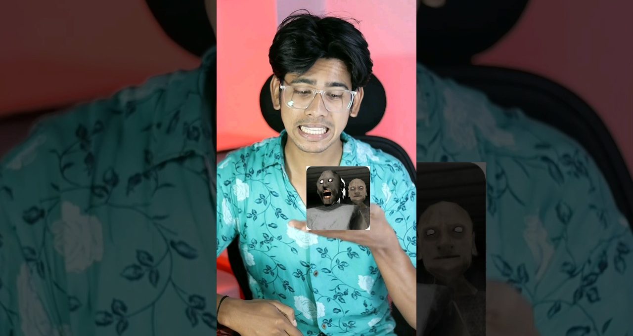 Young man in glasses reacting nervously while holding a phone showing a horror game thumbnail