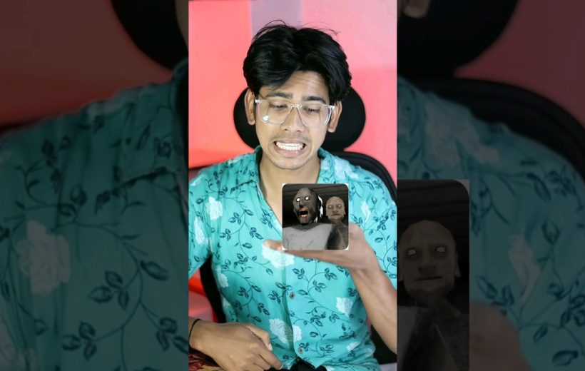 Young man in glasses reacting nervously while holding a phone showing a horror game thumbnail