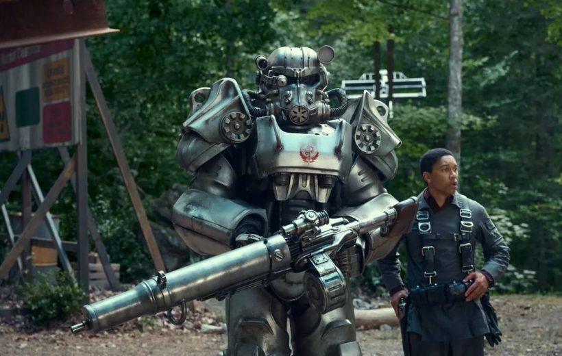 Armored power-suit soldier holding a large rifle beside a man in harnessed uniform