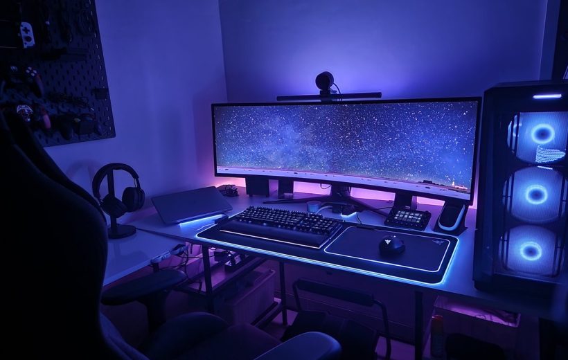 Gaming PC setup with ultrawide monitor, RGB lighting, mechanical keyboard, and headset.