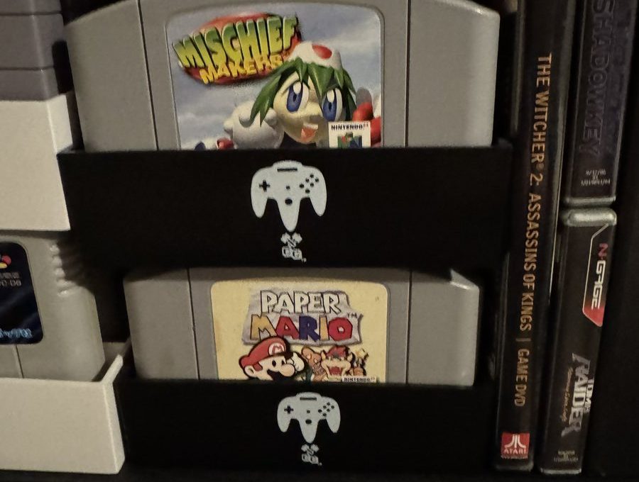 Stacked Nintendo 64 cartridges including Mischief Makers and Paper Mario in a shelf organizer