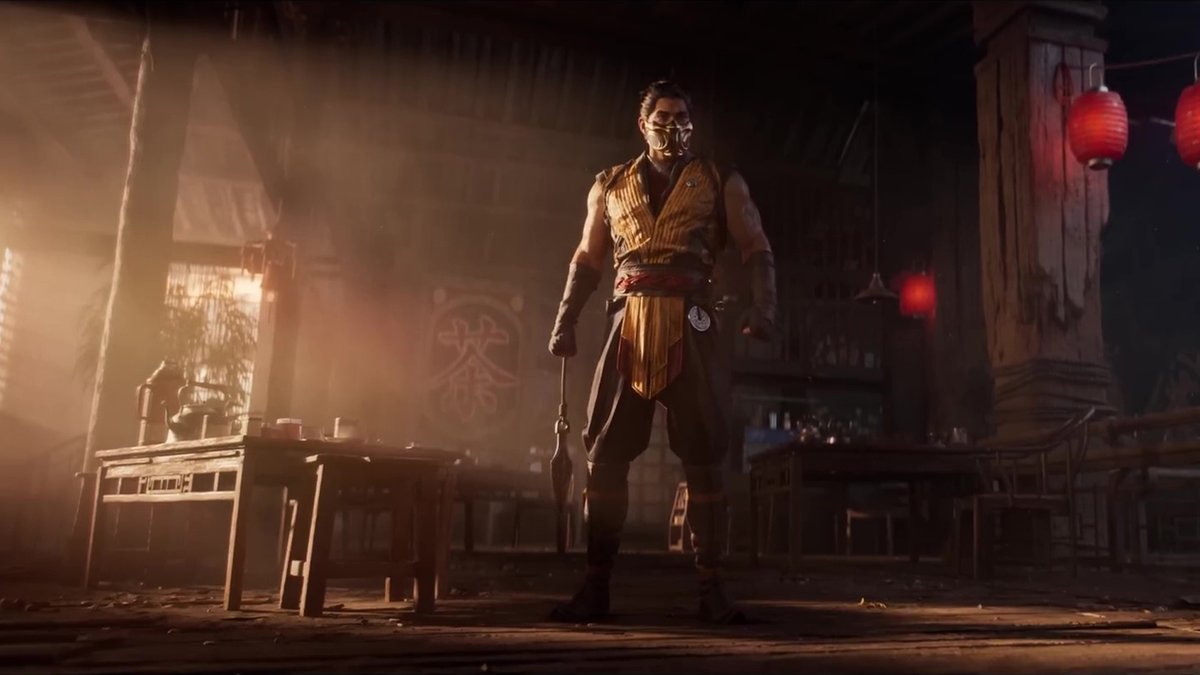 Masked warrior in yellow tunic holding a weapon, standing in a dimly lit tavern.
