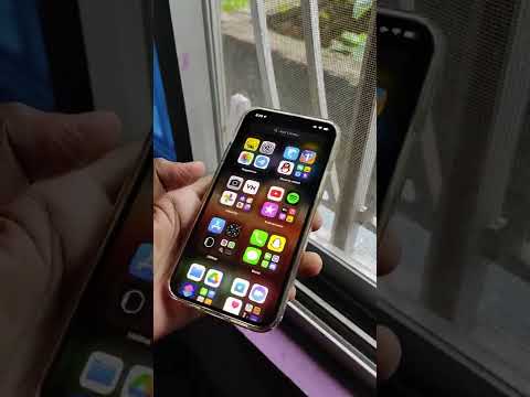Hand holding smartphone displaying colorful app grid near a window with bars