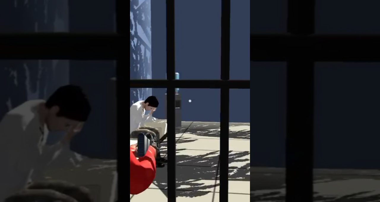 Man in white shirt sitting on floor behind bars while someone films him.