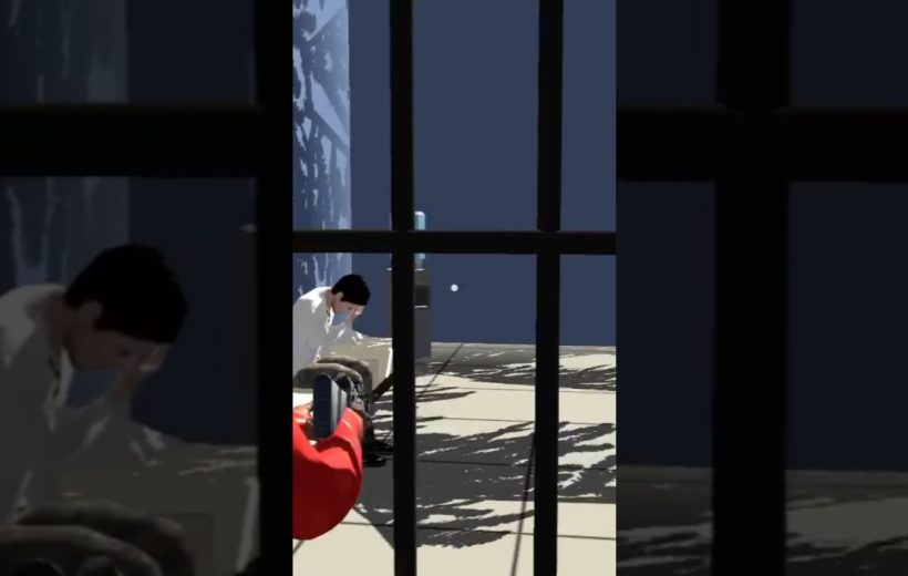 Man in white shirt sitting on floor behind bars while someone films him.