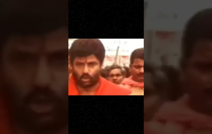 Bearded man in orange clothing leading a crowd of people outdoors during procession