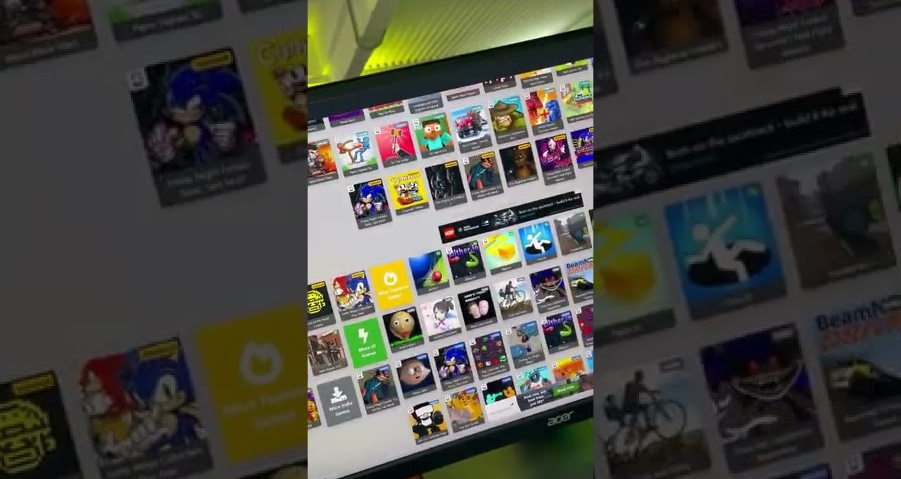 Desktop monitor displaying a grid of colorful game thumbnails and app icons on screen