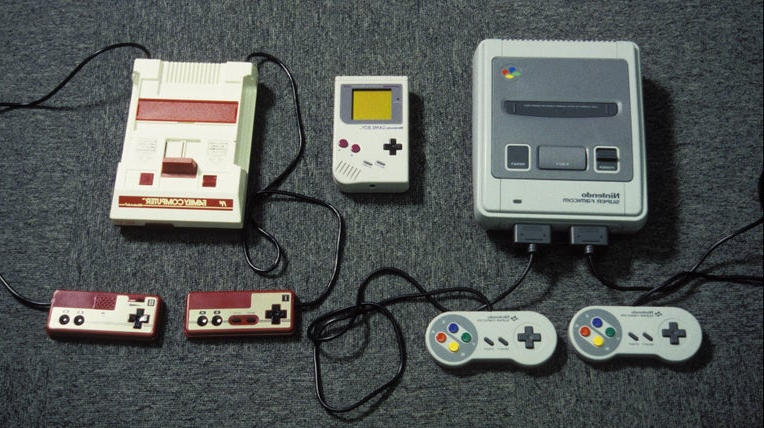 Two retro Nintendo consoles and controllers, Famicom, Game Boy, and Super NES laid out
