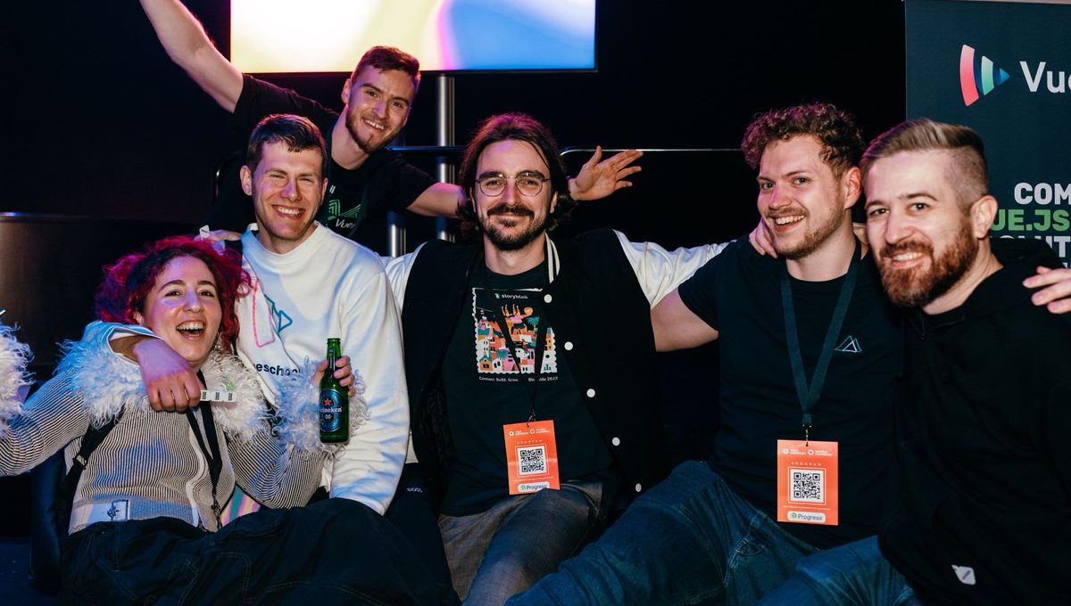 Group of smiling conference attendees posing together, some wearing event badges and lanyards
