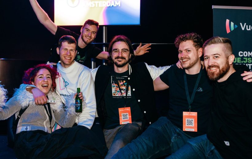 Group of smiling conference attendees posing together, some wearing event badges and lanyards