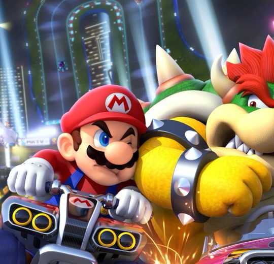 Mario and Bowser racing karts at night with fireworks over a neon track