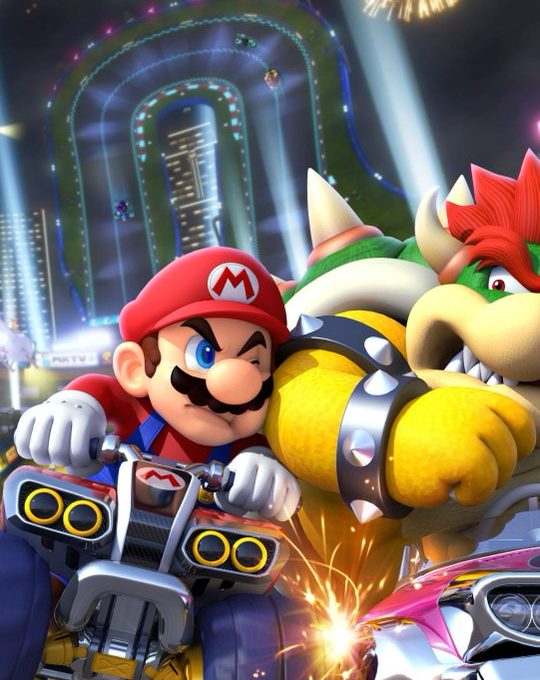 Mario and Bowser racing karts at night with fireworks over a neon track