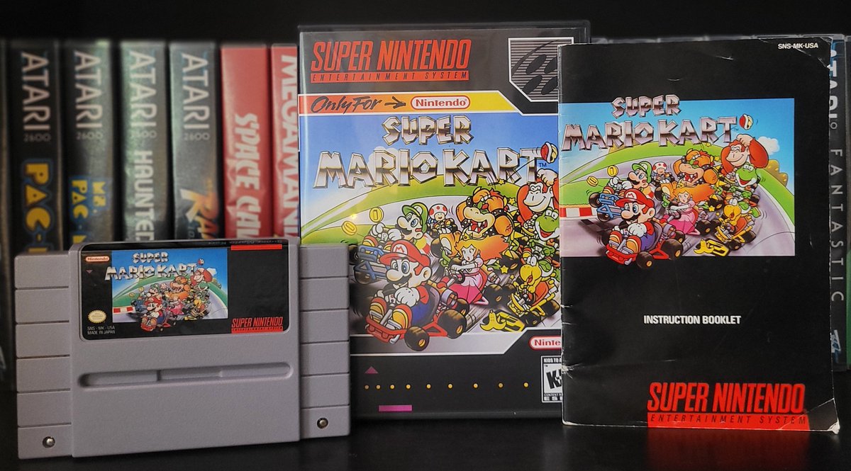 Super Mario Kart SNES cartridge, box, and instruction booklet displayed on shelf.